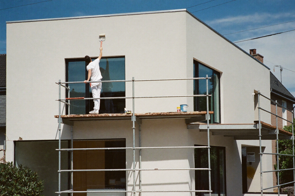 Maler Lauer streicht die Fassade eines modernen Wohnhauses vom Geruest in Oberaula